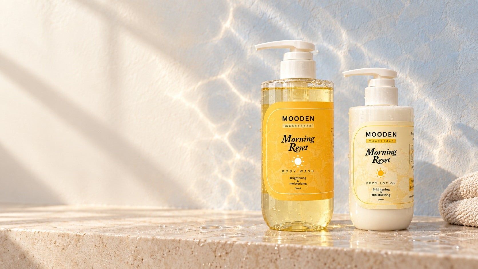 Morning Reset body wash and lotion in soft sunlight beside a folded towel